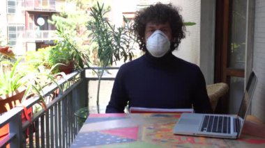 Avrupa, İtalya, Milano - İnsan 40 yaşında evde maske takıyor 19 Coronavirus salgını karantinası sırasında - evde çalışıyor ve İspanya bayrağının enfekte olduğunu gösteriyor