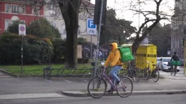 İtalya, Milan - 21 Ocak 2020: Uber yiyecek yiyor - yeşil çanta kutusuyla sokağa çıkan bisiklet sürücüsü, Avrupa ve Amerika 'da (ABD) ve Asya' da 19 acil durum salgını sırasında devam ediyor