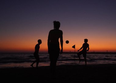 Gün batımında sahilde bir ailenin silueti.