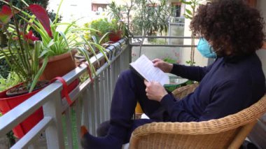 Adam elinde çiçeklerle sandalyede oturuyor.