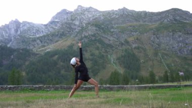 Dağlarda yoga yapan bir kadın.