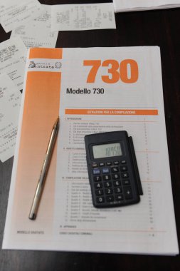 Milan, Italy september 27,2018 - tax and income tax return - 730 ( Unico ) - money and calculator - n-cov19 Coronavirus epidemic, state subsidy for self-employed workers (VAT numbers) and employees