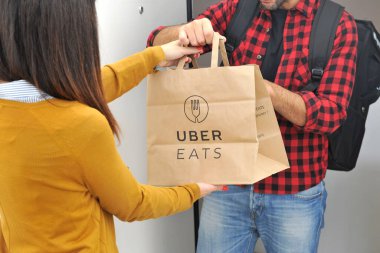 Milan - Uber yiyecek teslimatları, alışveriş torbası taşıyan bir kadın