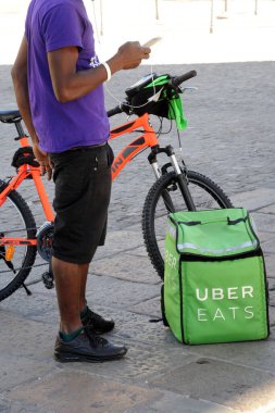 Sokakta bisikletli bir adam, Uber yemek yiyor.