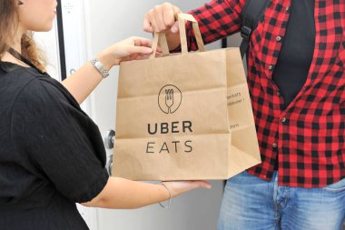 Kadın alışveriş poşetini mesajla tutuyor, Uber yiyor.