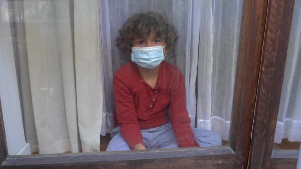 在欧洲 美洲和亚洲 6岁的白人白人男孩被关在隔离院 戴着口罩 从房子的窗户向外张望 — 图库视频影像
