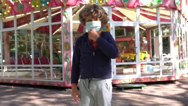 在公园里 小男孩头戴面罩 在操场上愁眉苦脸 — 图库视频影像
