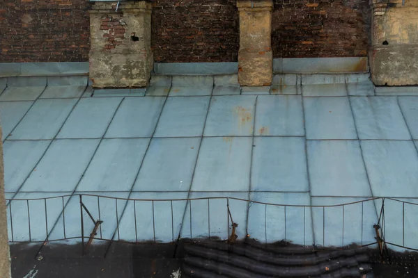 Büyük bir şehirde, duvarları ve bacaları olan eski bir evin çatısında.