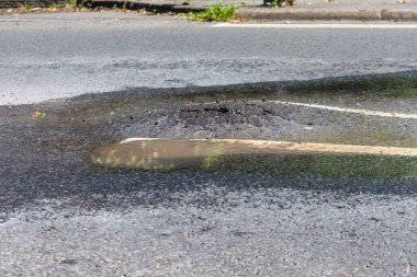 Yol yüzeyinin altında bir su borusu ya da patlak bir su borusu yukarı itiyor ve pisti yarıyor ve yola su sızdırıyor.