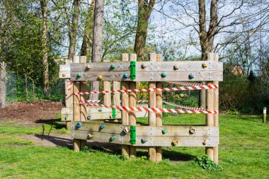 Korona virüsünün tecrit edilmesini önlemek için bantlanmış bir parktaki ahşap tırmanma ve egzersiz ekipmanı.