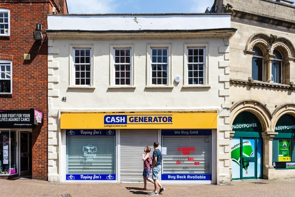 Kapalı bir CashGenerator mağazası. Pencerelerin içinde çelik güvenlik jaluzileri var. Bir çift de pencerede bir uyarı okuyor.