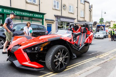 Kırmızı renkli Polaris sapanlı trike 'ın ön tarafı. Arkasında tek tekerlek olan bir motorsiklet. Calne Motosikleti 2019 'da