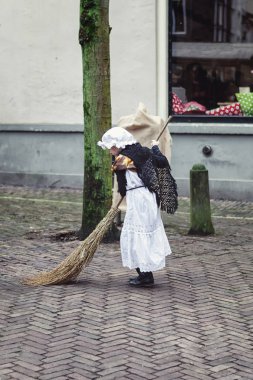 Deventer, Hollanda, 21 Aralık 2014: Victoria kostüm elbiseli küçük kız Deventer Dickens Festivali sırasında caddenin bir süpürge ile piyango