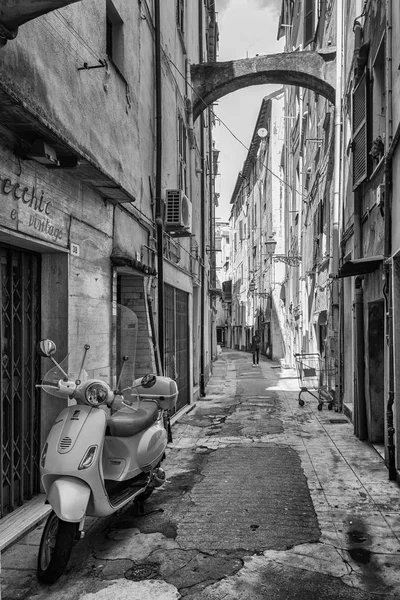 Black White picture of a scooter parked in the narrow street Via Bezzecca in the center of the Italian town San Remo.