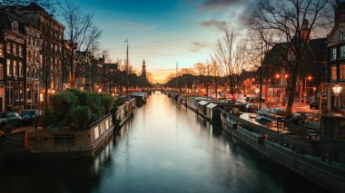 Gün batımı nda arka planda Westertoren kulesi ile Amsterdam'ın eski merkezinde Prinsengracht Houseboats