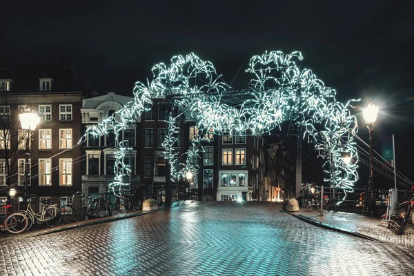 Jättespindel av vitt ljus ovanför en bro över Herengracht i den gamla staden Amsterdam — Stockfoto