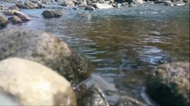 Bol suyu olan bir nehirde su akışı sakindir. Doğal taşların arasından akan bir su akıntısı. Suyun Fast Splash 'inde Rock Rapid. Yogyakarta, Kali Opak. Ekran Görüntüsü Tam HD