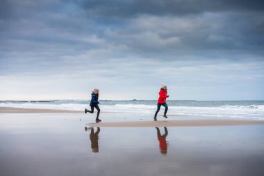 Kumsalda annesini kovalayan bir kız.