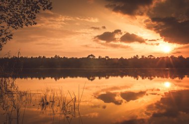 Sonbaharda günbatımı Nehri Deltası üzerinde. Sonbahar akşam yatay, sazlık ve saman ile çevrili bir göl