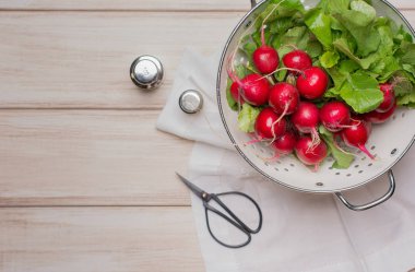 Taze ıslak turp üzerinde beyaz kevgir içinde eski bir ahşap masa. Köy tarzı. Karanlık anahtar fotoğraf.
