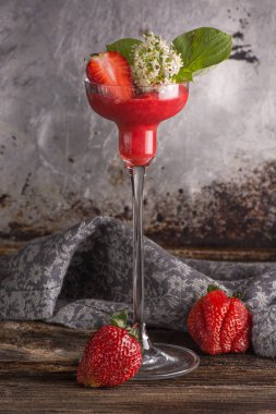 Ahşap ve metal arka plan üzerinde çilek güler yüzlü uzun saplı bardak. Glamour.