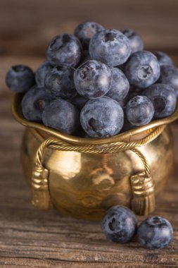 Ahşap ve metal arka plan üzerinde cooper kapta yaban mersini. Glamour.