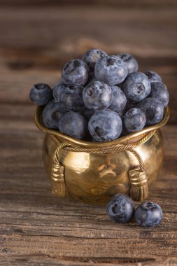 Ahşap ve metal arka plan üzerinde cooper kapta yaban mersini. Glamour.