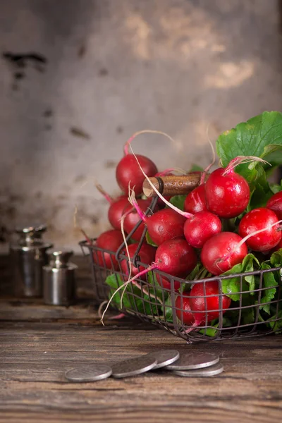 Fresh wet radishes in a basket on the an old wooden table. Village style. Dark key photo.