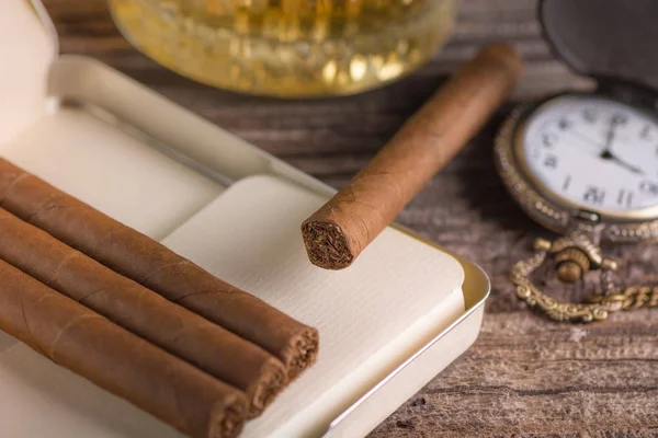 Sigara ve viski ahşap zemin üzerinde cam metal kutu