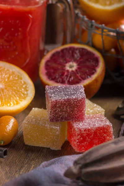 Sweet sugary fruit flavored jellies. Homemade citreous marmalade of different colors and fresh orange fruits. Rustic style. Close view