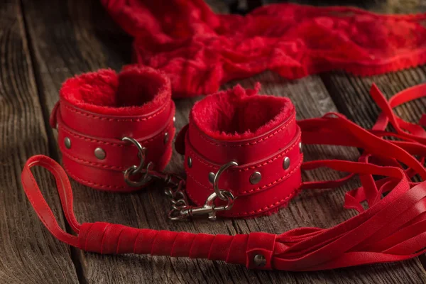 BDSM kırmızı kelepçe, scourge ve iç çamaşırı üzerinde siyah bir arka plan, esaret öğesi ortak hareketsiz. Seks shop.