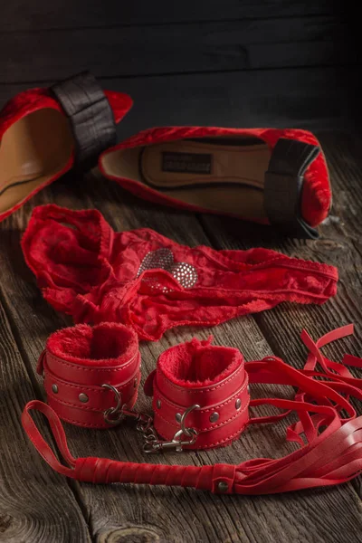 BDSM kırmızı kelepçe, scourge ve iç çamaşırı üzerinde siyah bir arka plan, esaret öğesi ortak hareketsiz. Seks shop.