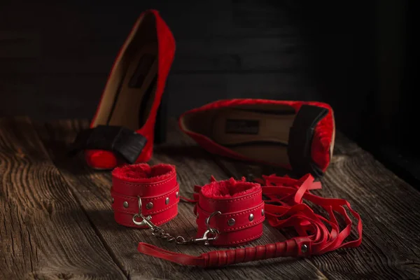 BDSM kırmızı kelepçe, scourge ve iç çamaşırı üzerinde siyah bir arka plan, esaret öğesi ortak hareketsiz. Seks shop.