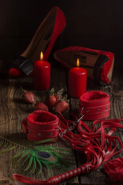 BDSM kırmızı kelepçe, scourge ve iç çamaşırı üzerinde siyah bir arka plan, esaret öğesi ortak hareketsiz. Seks shop.