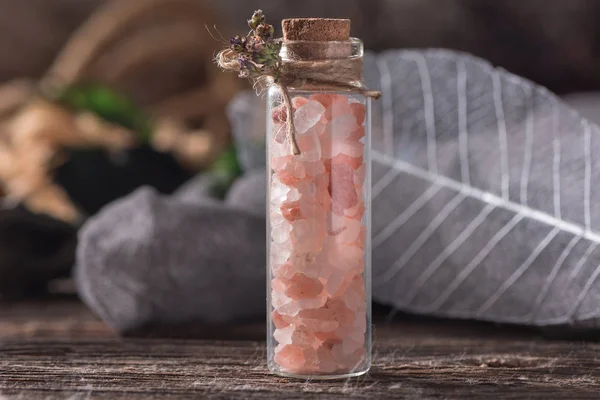 Küçük cam şişe mantarı ahşap masa üzerinde pembe tuz. Görünümü kapat. Seçici odak.