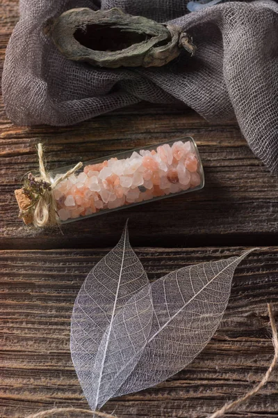 Küçük cam şişe mantarı ahşap masa üzerinde pembe tuz. Görünümü kapat. Seçici odak.