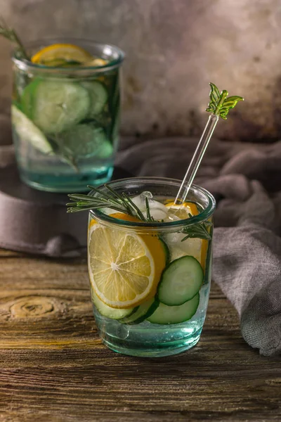 Detox fruit infused water. Refreshing summer homemade cocktail, selective focus. Wooden rustic background. Cold and refreshing detox water with lemon and cucumber.