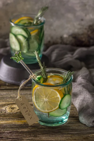 Detox fruit infused water. Refreshing summer homemade cocktail, selective focus. Wooden rustic background. Cold and refreshing detox water with lemon and cucumber.