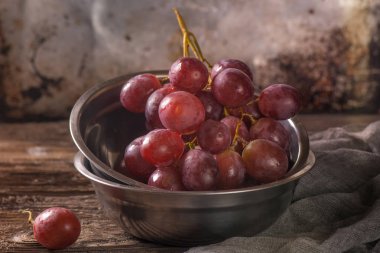 Paslanmaz vintage Kupası'nda kırmızı üzüm ile natürmort. Koyu arka plan, seçici odak. Görünümü Kapat.