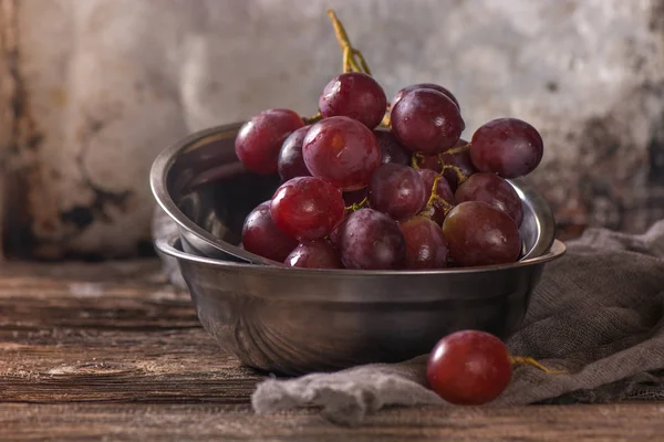 Paslanmaz vintage Kupası'nda kırmızı üzüm ile natürmort. Koyu arka plan, seçici odak. Görünümü Kapat.