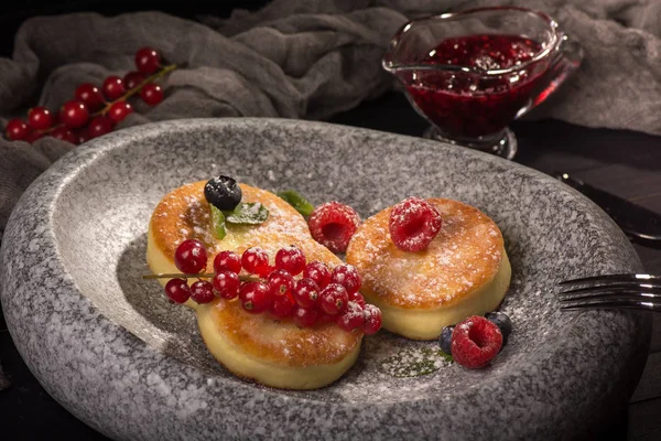Cottage cheese pancakes or fritters with cherry sauce and berries. Traditional Ukrainian and Russian cuisine. Syrniki. Healthy and diet breakfast.