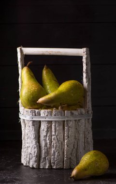 Koyu arka planda armut ile Orijinal beyaz sepet. Koyu fotoğraf stili.