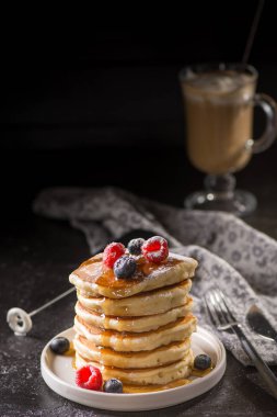 Berry soslu krep ve koyu arka plan üzerinde meyveleri. Krep yığını yaban mersini, çilek ve tatlı sos ile. Closeup görünümü