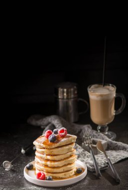 Berry soslu krep ve koyu arka plan üzerinde meyveleri. Krep yığını yaban mersini, çilek ve tatlı sos ile. Closeup görünümü