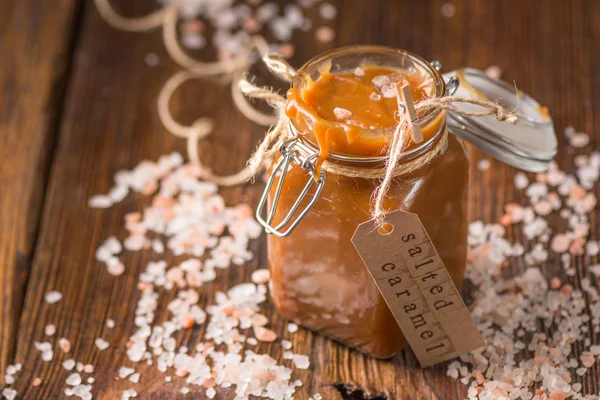 Cam kavanozda ev yapımı tuzlu karamel sosu. Seçici odaklama, metin için alan