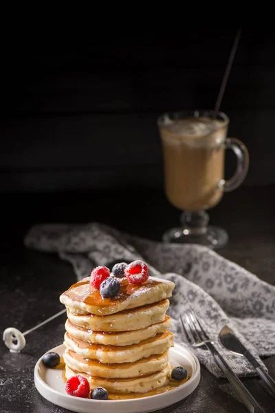 Berry soslu krep ve koyu arka plan üzerinde meyveleri. Krep yığını yaban mersini, çilek ve tatlı sos ile. Closeup görünümü