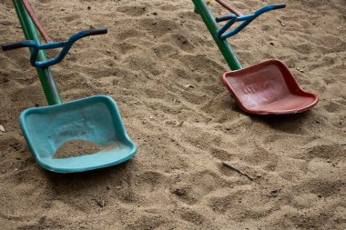 Oyun parkındaki kumun üzerinde duran iki testere koltuğu