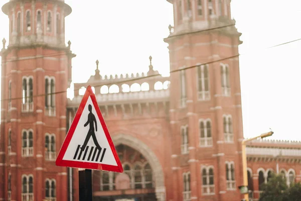 Pedestrian crossing sign board on the road in front of a monument during daylight