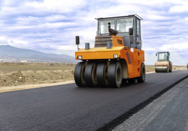 Yol silindiri bulutlu mavi gökyüzü ile yol inşaat sahasında