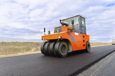 Yol silindiri bulutlu mavi gökyüzü ile yol inşaat sahasında